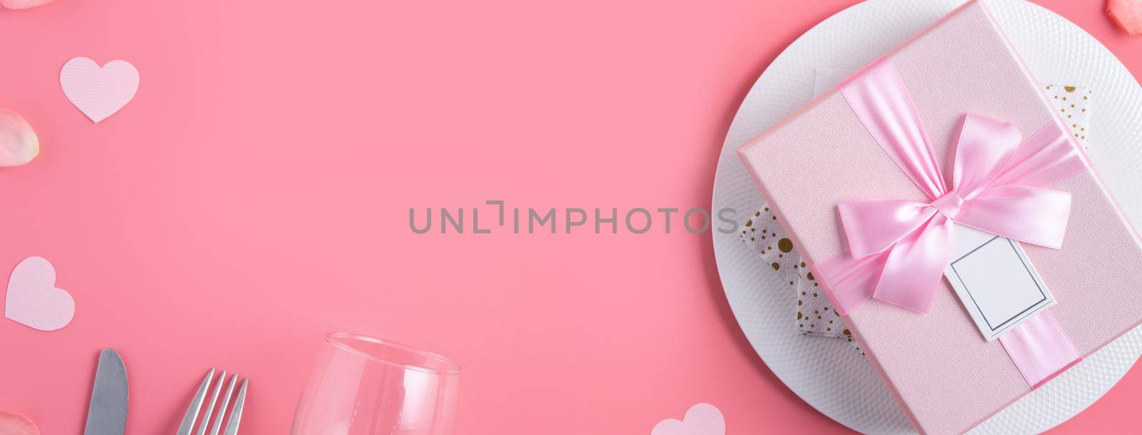Empty white plate with gift and rose petals for Valentine's Day special holiday dating meal concept.