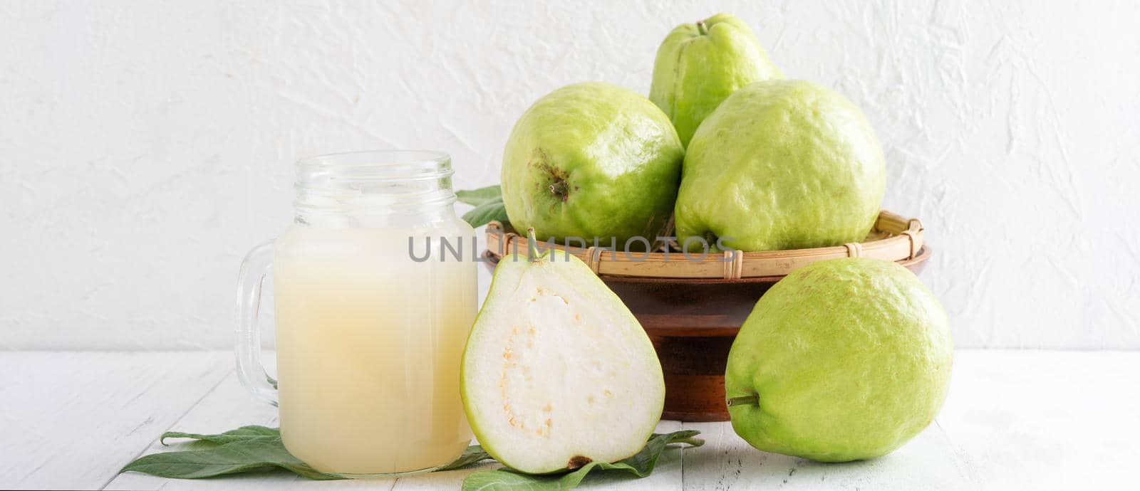 Delicious beautiful guava fruit with fresh juice set isolated on bright white wooden table background, close up.