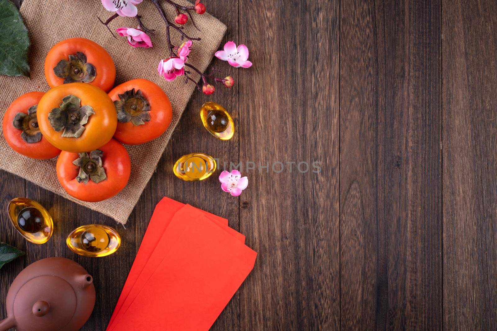 Top view of fresh sweet persimmons kaki with leaves on wooden table background for Chinese lunar new year fruit design concept, the word means blessing is coming.