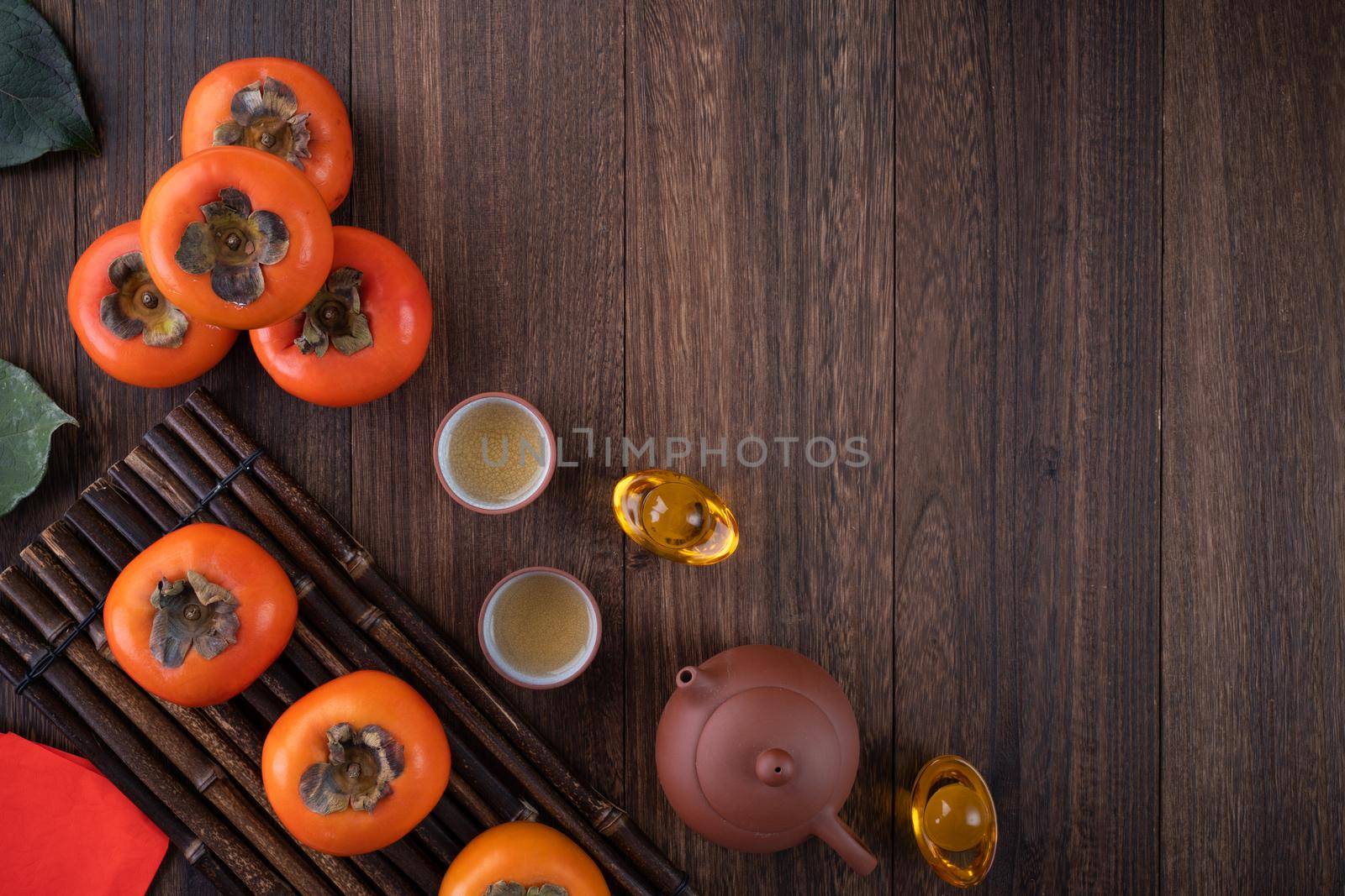 Top view of fresh sweet persimmons kaki with leaves on wooden table background for Chinese lunar new year fruit design concept, the word means blessing is coming.