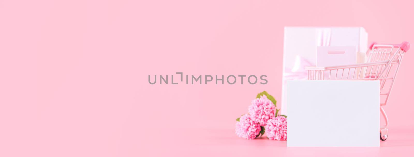 Mother's Day holiday gift design concept, pink carnation flower bouquet with wrapped gift box isolated on pink background, copy space.