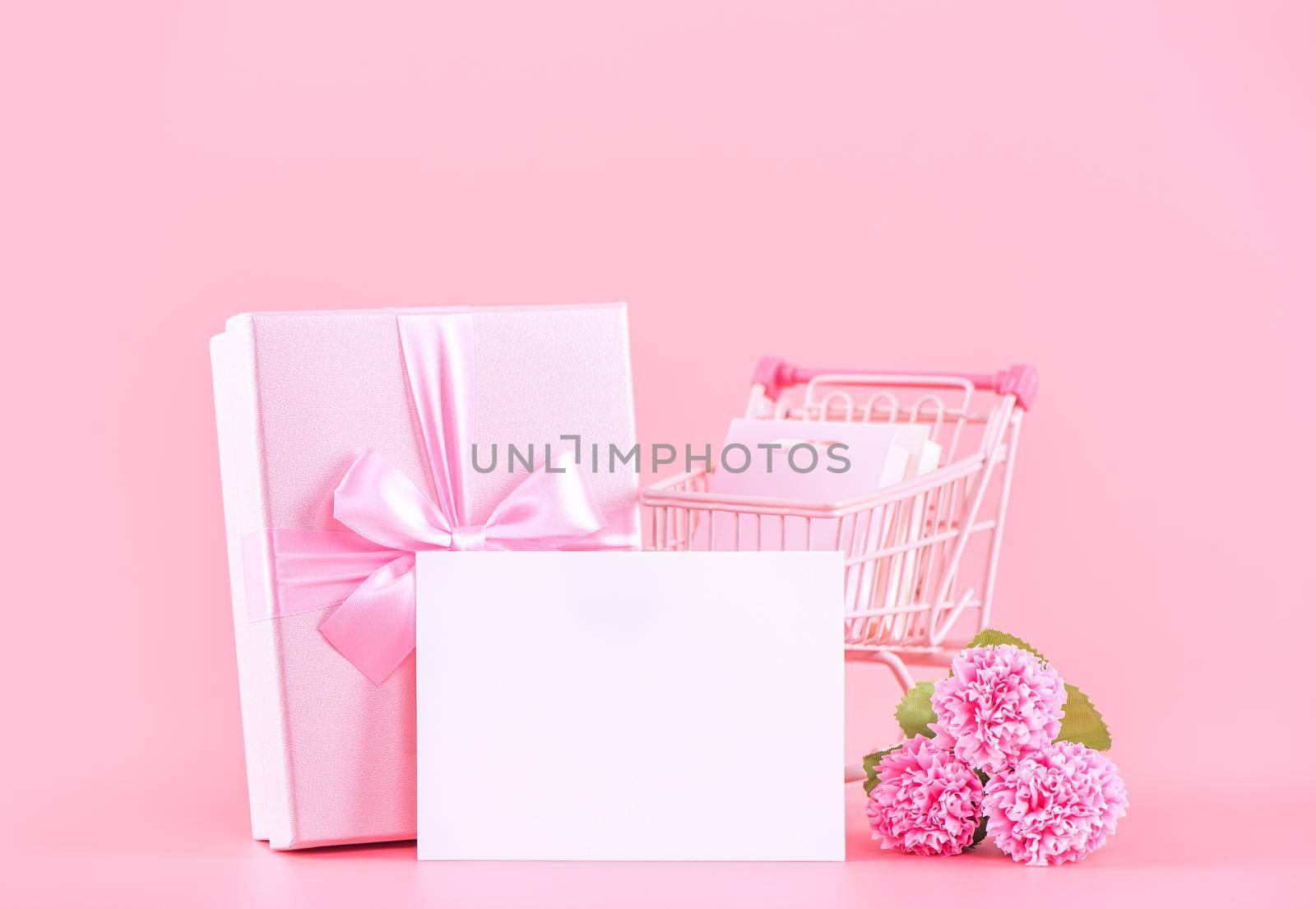 Mother's Day holiday gift design concept, pink carnation flower bouquet with wrapped gift box isolated on pink background, copy space.