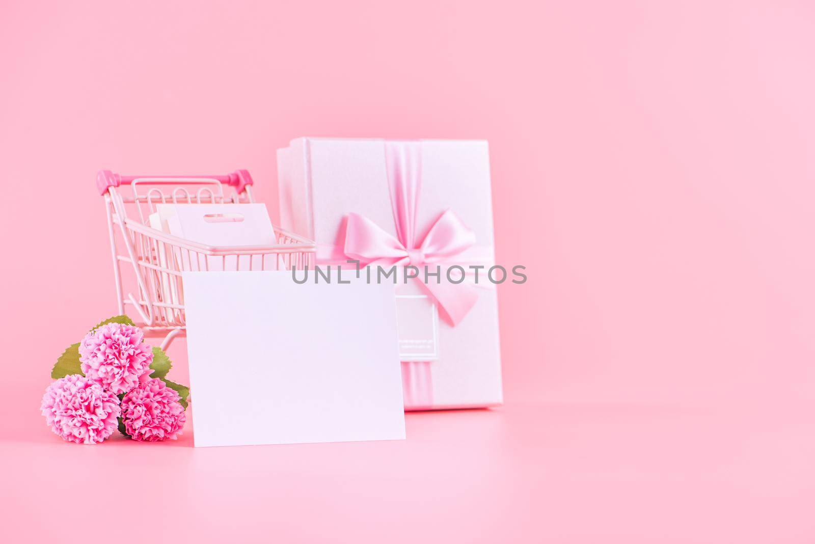 Mother's Day holiday gift design concept, pink carnation flower bouquet with wrapped gift box isolated on pink background, copy space.
