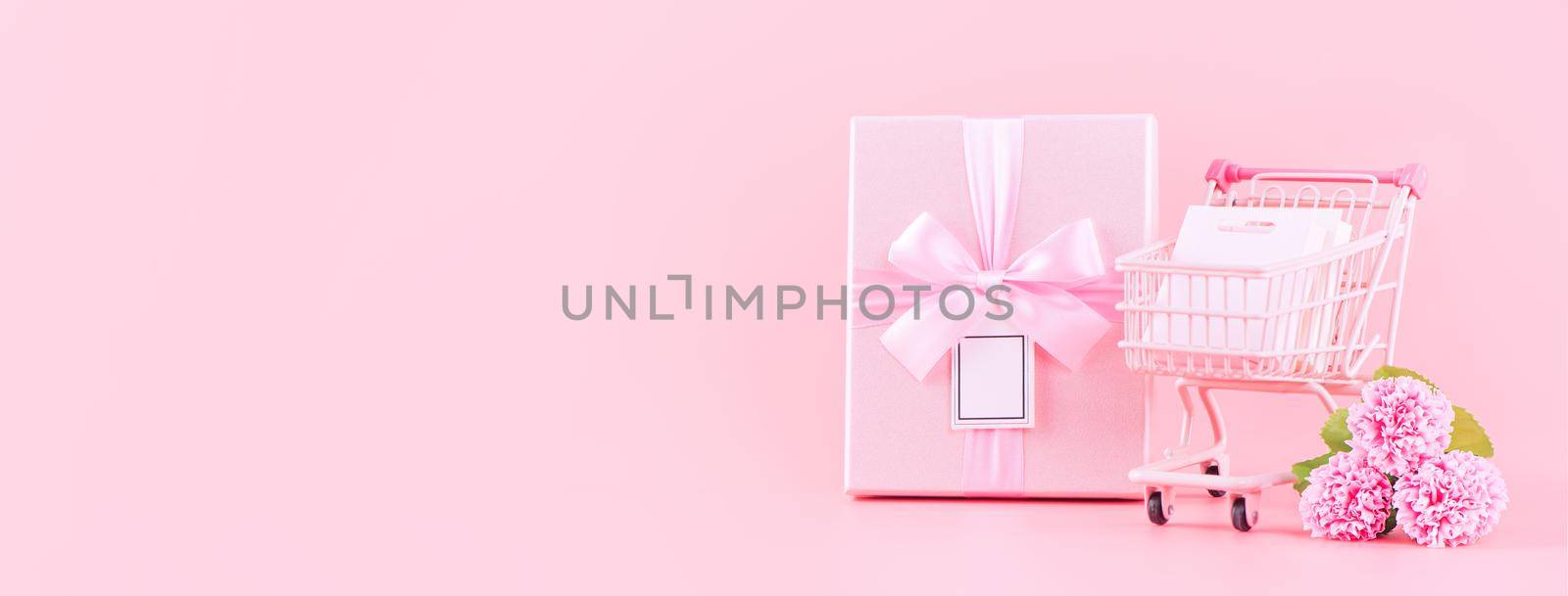 Mother's Day holiday gift design concept, pink carnation flower bouquet with wrapped gift box isolated on pink background, copy space.