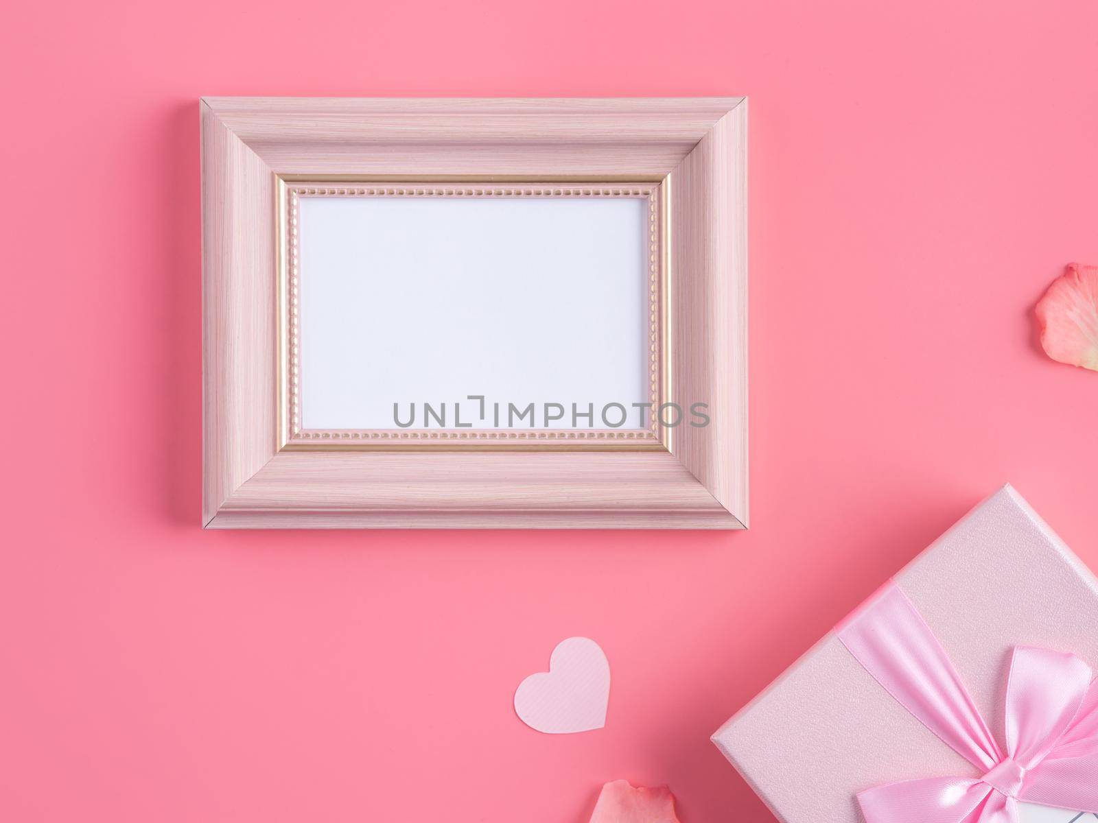 Valentine's Day design concept background with pink petals and gift box on pink background