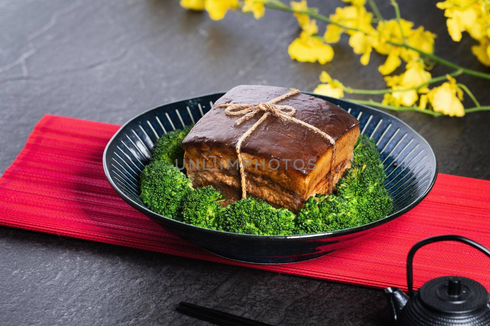 Dong Po Rou (Dongpo pork meat) in a beautiful blue plate with green broccoli vegetable, traditional festive food for Chinese new year cuisine meal, close up.