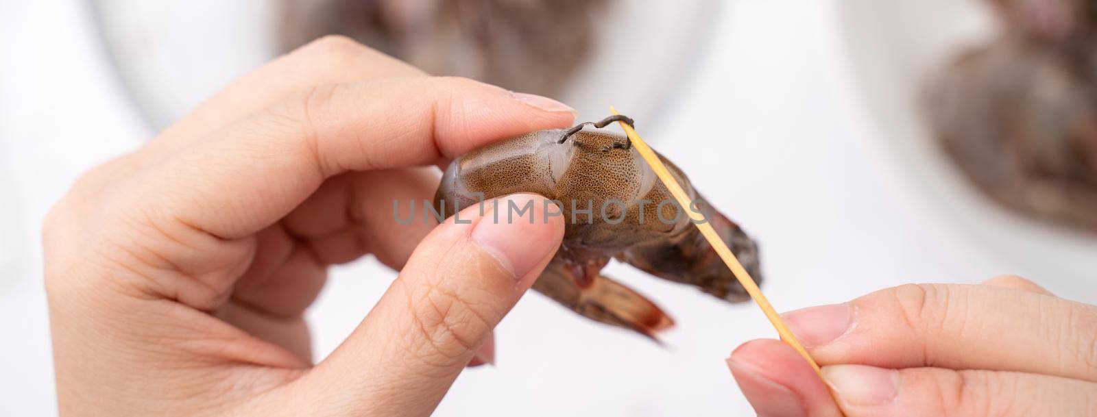 Woman deveins shrimp and pull out intestinal tract line when cooking shrimp.