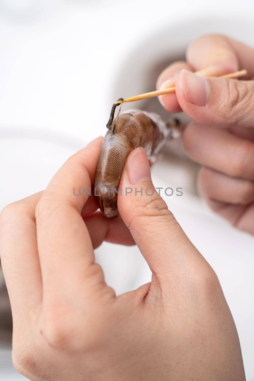 Woman deveins shrimp and pull out intestinal tract line when cooking shrimp.