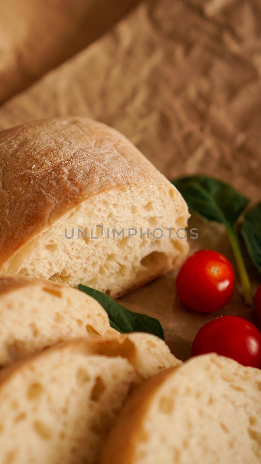 Ciabatta slices and cherry tomatoes on craft paper. Cooking healthy snacks. Ingredients for bruschetta