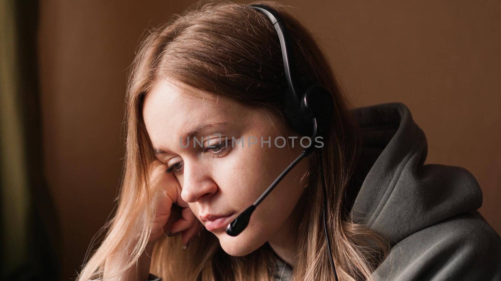 Portrait of young girl in a hoodie and with a headset. Tired call center worker by natali_brill