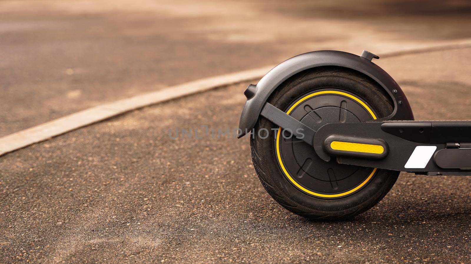 Close-up photo of the rear wheel of an electric scooter against the background of asphalt