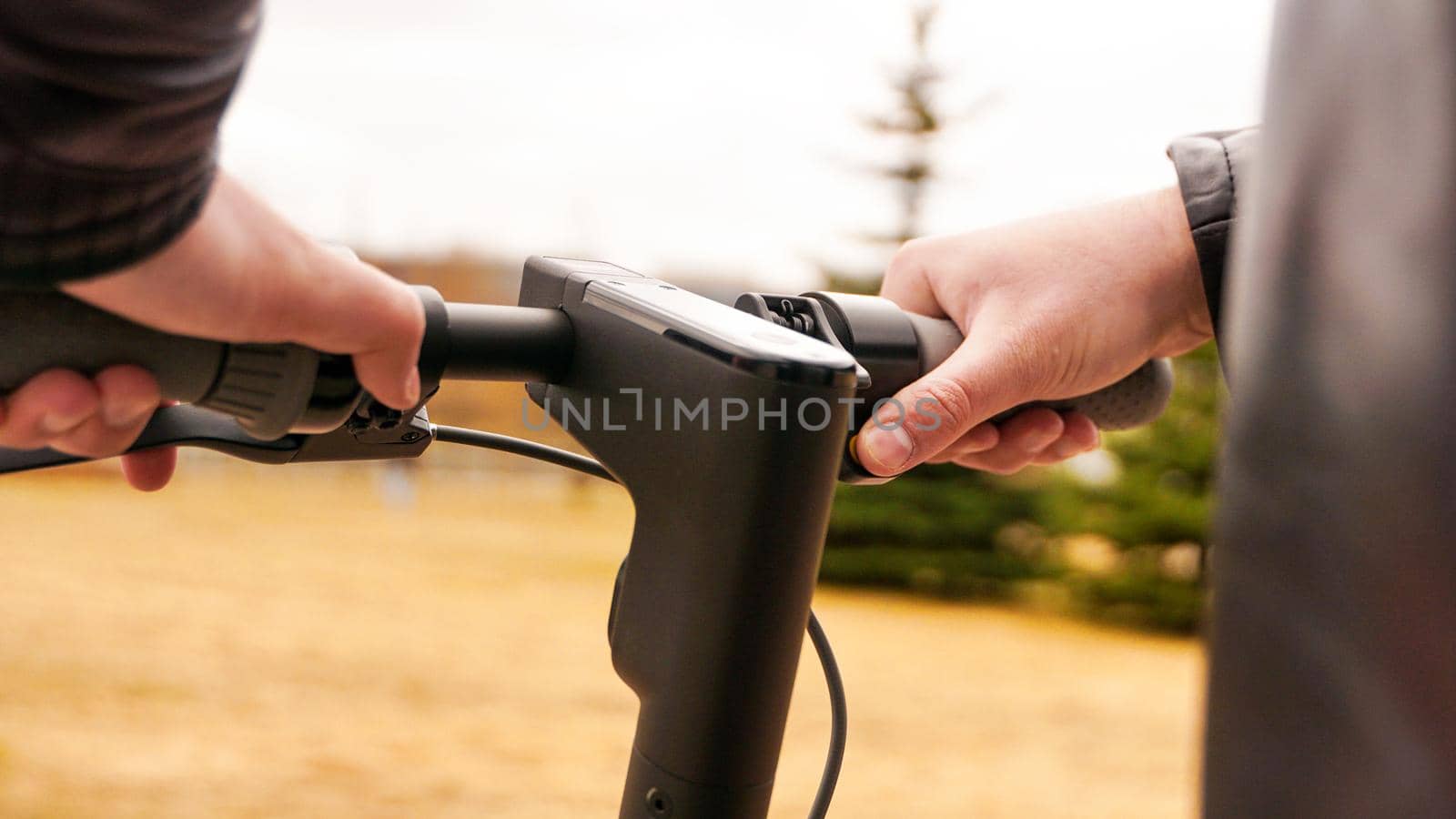 Close-up of male hand pressing speed button on electric scooter. Photo outdoors in the park