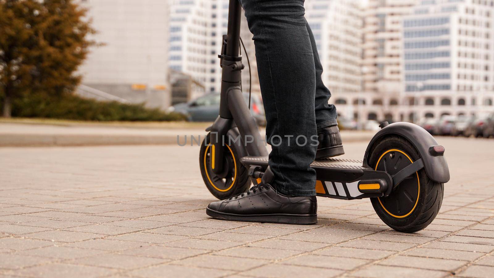 Cropped image of young man riding in the street on electric kick scooter by natali_brill