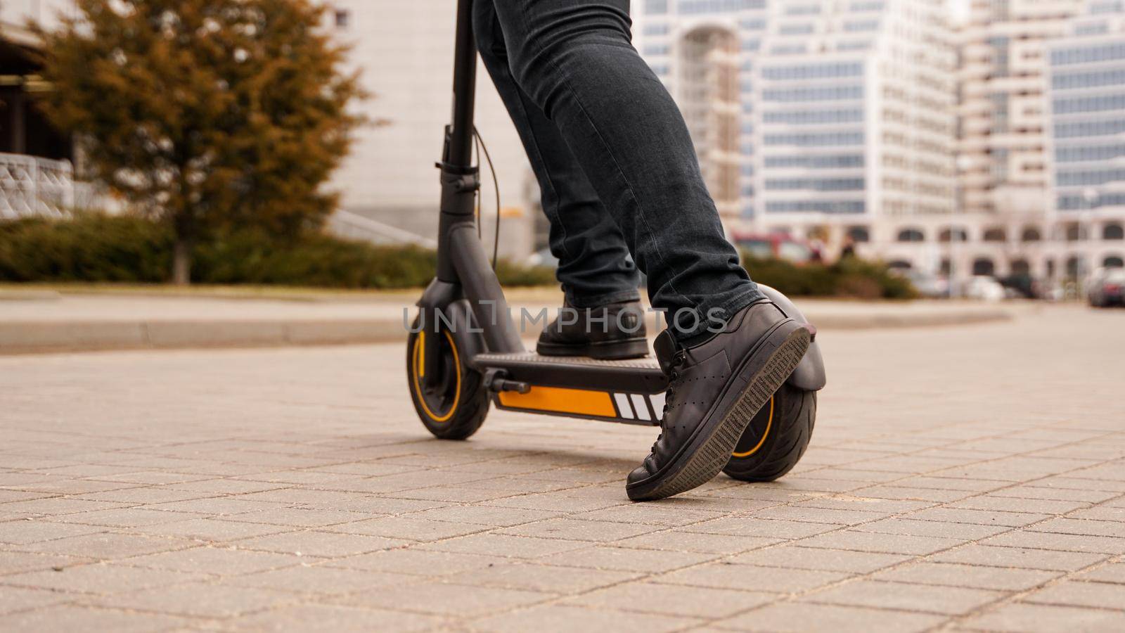 Cropped image of young man riding in the street on electric kick scooter by natali_brill