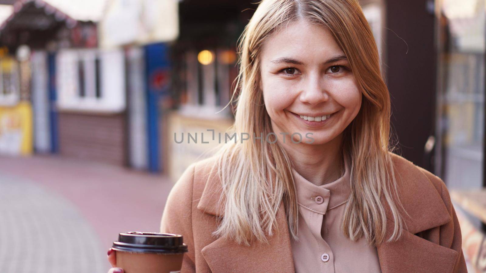 Young blonde with a cup of coffee. Woman at the food court. Lifestyle photo. Beautiful woman drinking coffee