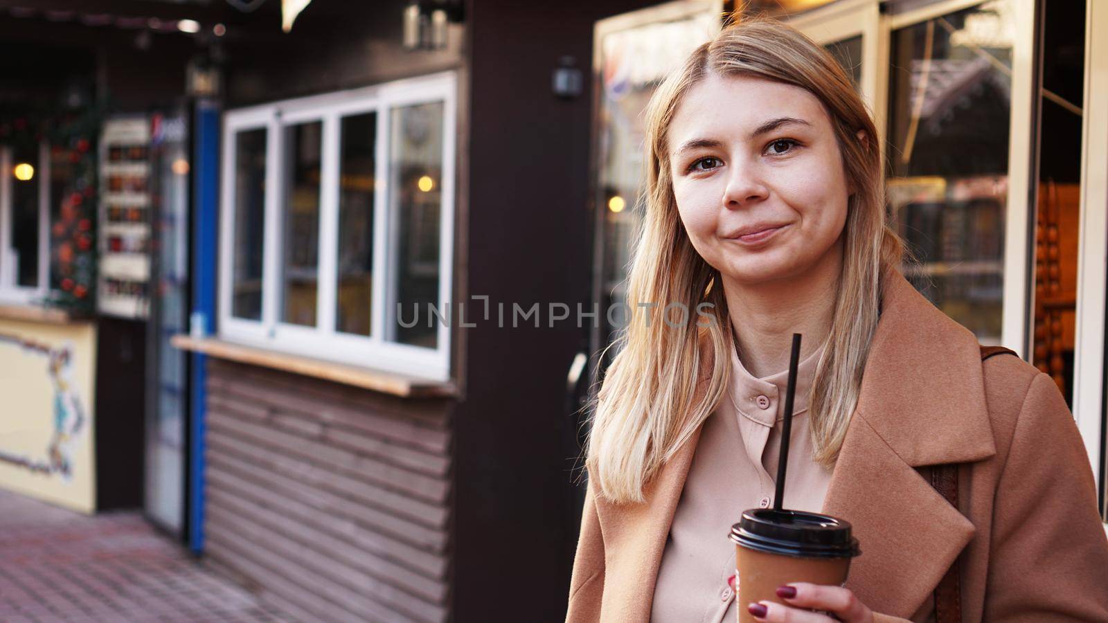 Young blonde with a cup of coffee. Woman at the food court. Lifestyle photo. Beautiful woman drinking coffee