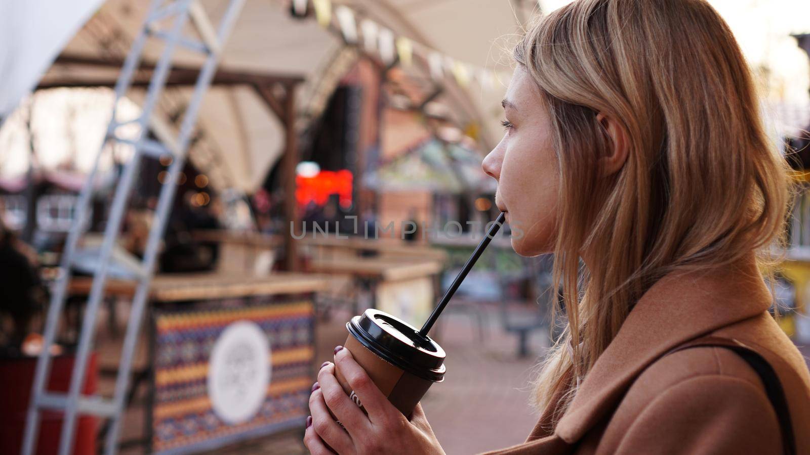 Young blonde with a cup of coffee. Woman at the food court. Lifestyle photo. Beautiful woman drinking coffee