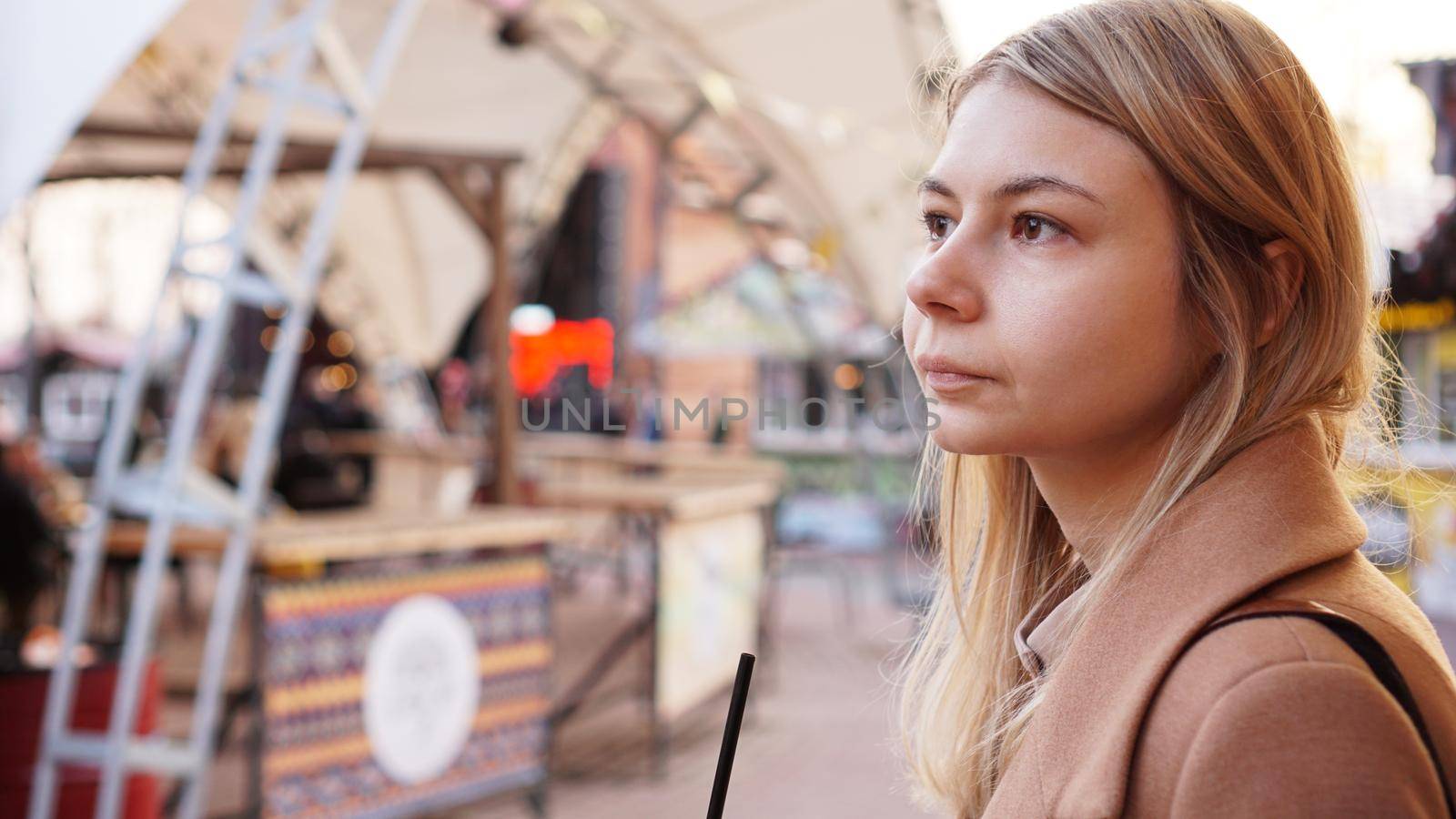 Portrait of a young woman in the city. City food court with street food. Portrait of a blonde. Lifestyle photo