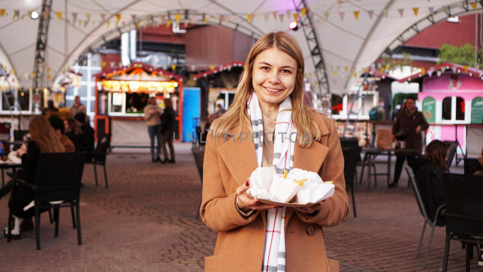 Woman at the food court with food trucks. The blonde has bought some street food by natali_brill