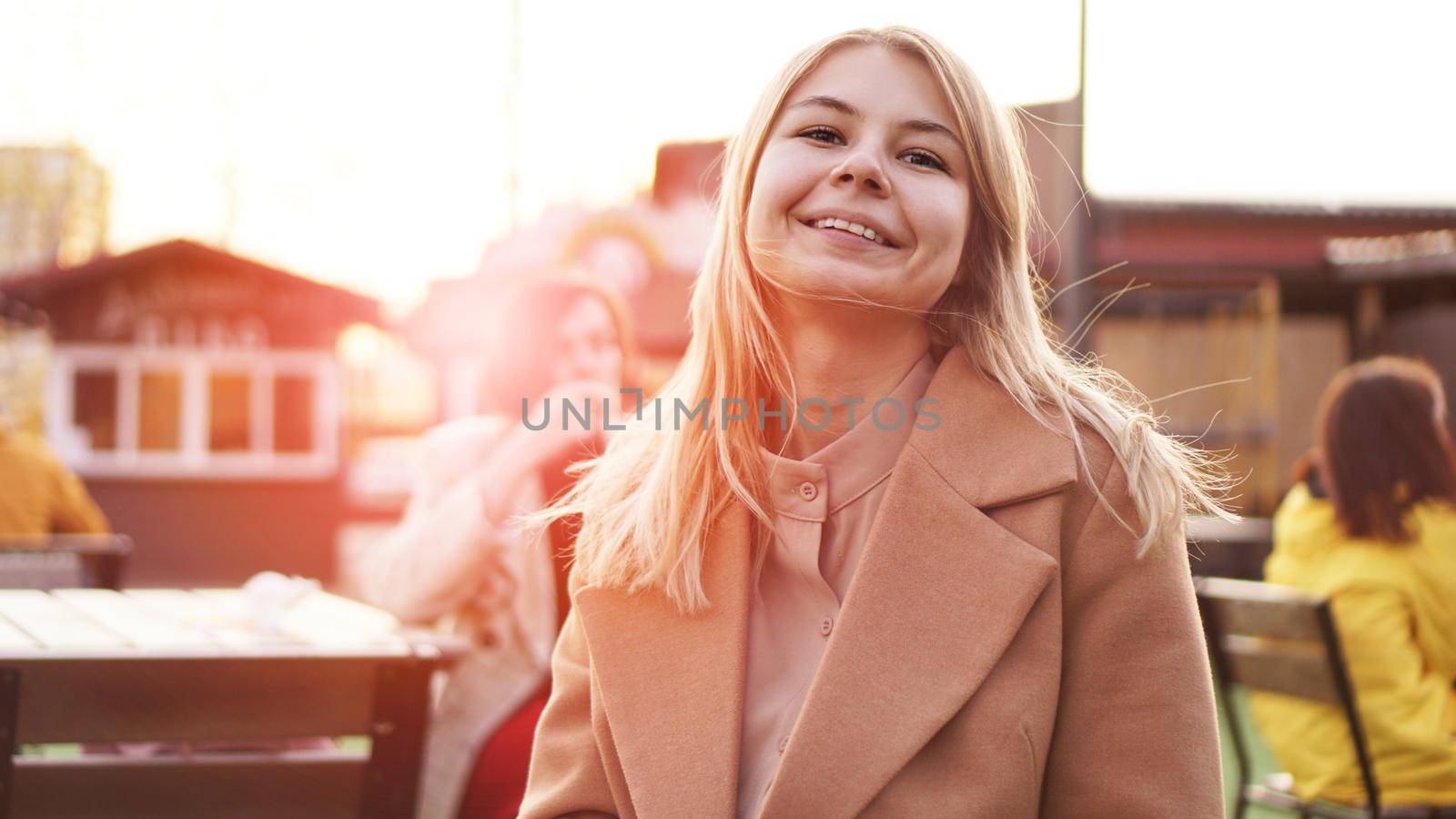 Portrait of a young woman in the city. City food court with street food. Portrait of a smiling blonde. Glare of the sun