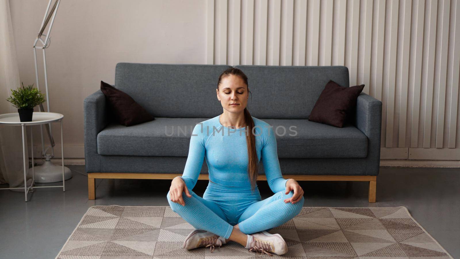 Time for yoga. Attractive young woman exercising and sitting in yoga position while resting at home