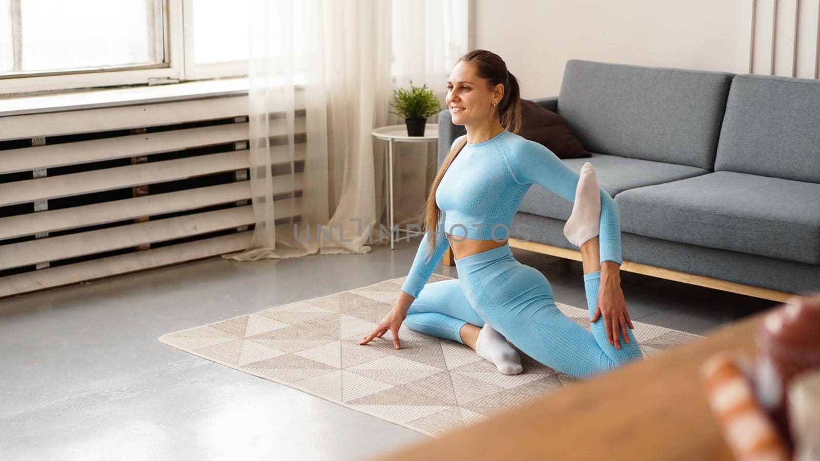 Mid adult woman training at home. Horizontal shape, full length, side view. Happy woman doing fitness and yoga at home.