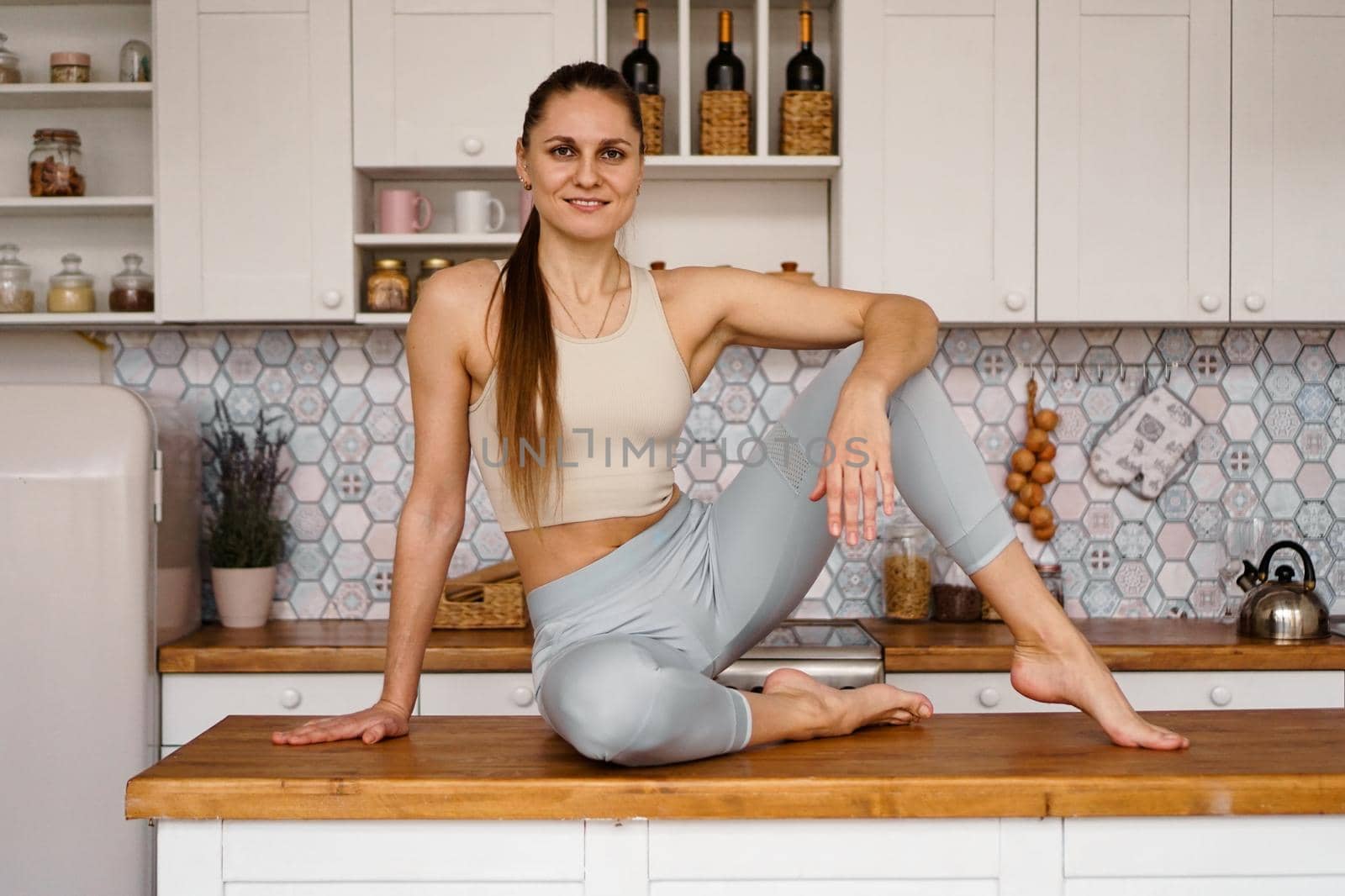 Athletic woman in sportswear posing on the table top. The concept of beauty, health, proper nutrition. Woman smiling and looking at the camera