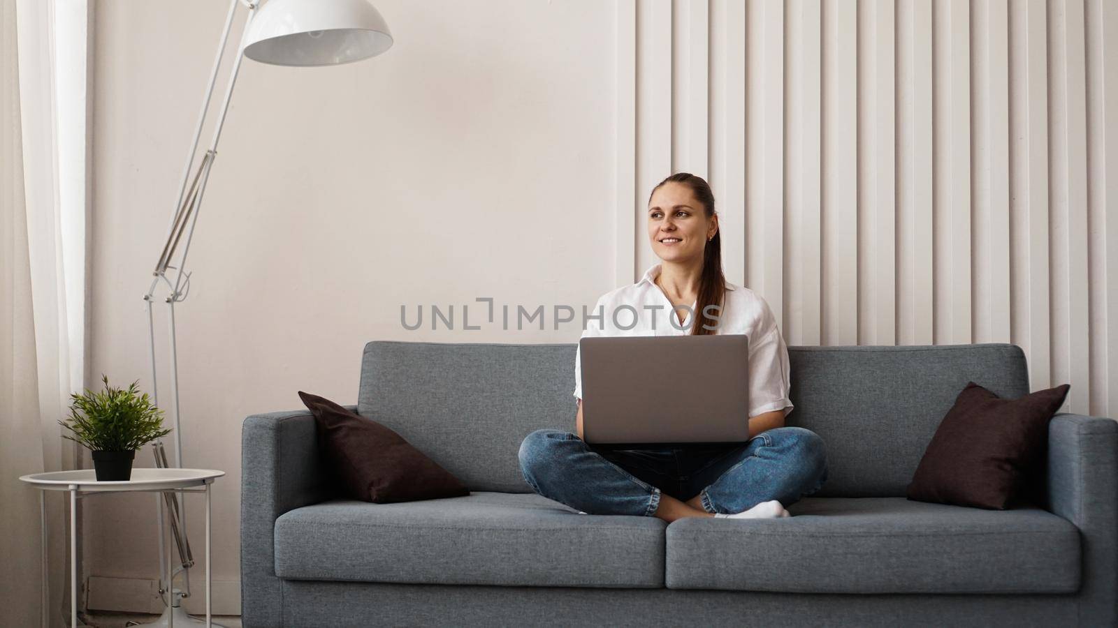 Woman working on laptop from home or student studying from home or freelancer. Modern business woman in a white shirt and jeans.