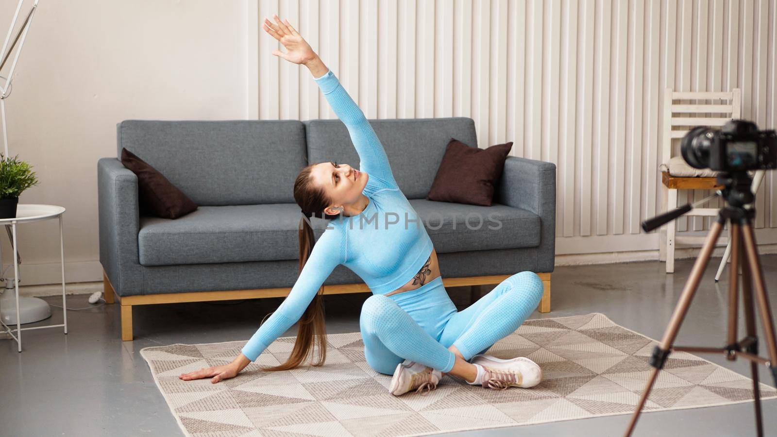 Athletic woman blogger in sportswear shoots video on camera at home in the living room. Sport and recreation concept. Healthy lifestyle.