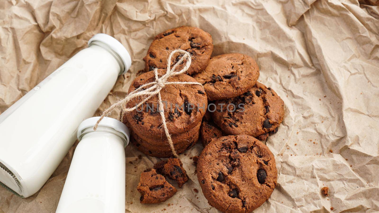 Cookies with chocolate drops on craft paper and bottles of milk. Natural handmade organic snakes for healthy breakfast