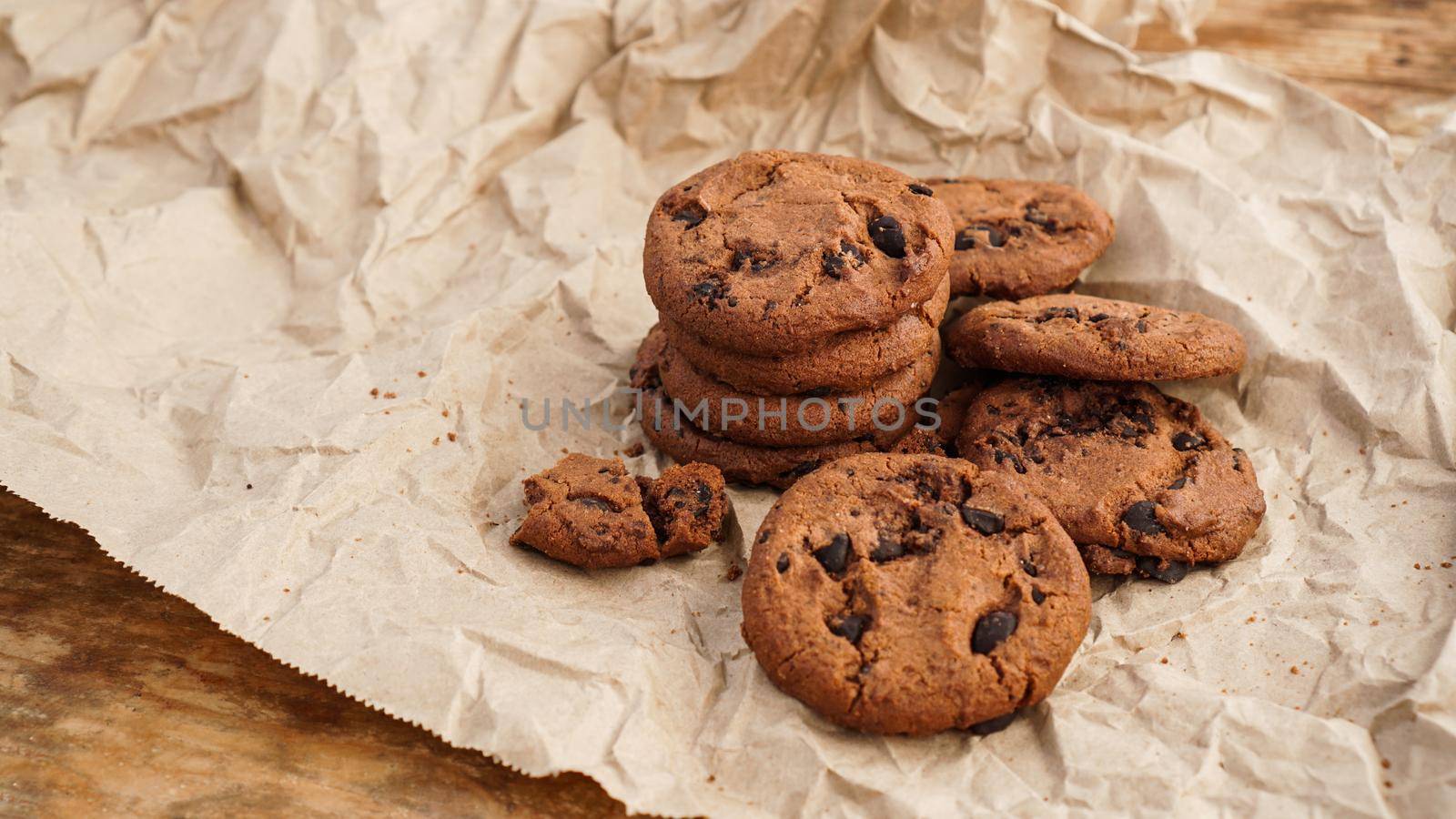 Flatview of handcrafted chocolate cookies with chocolate chips on baking paper. Natural handmade organic snakes for healthy breakfast