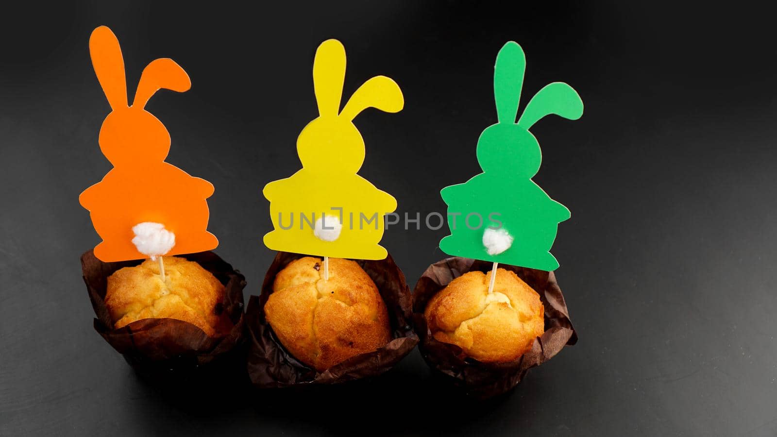 Muffin decorated with a paper rabbit on a toothpick. Easter decor for cupcakes. Festive sweets and pastries.