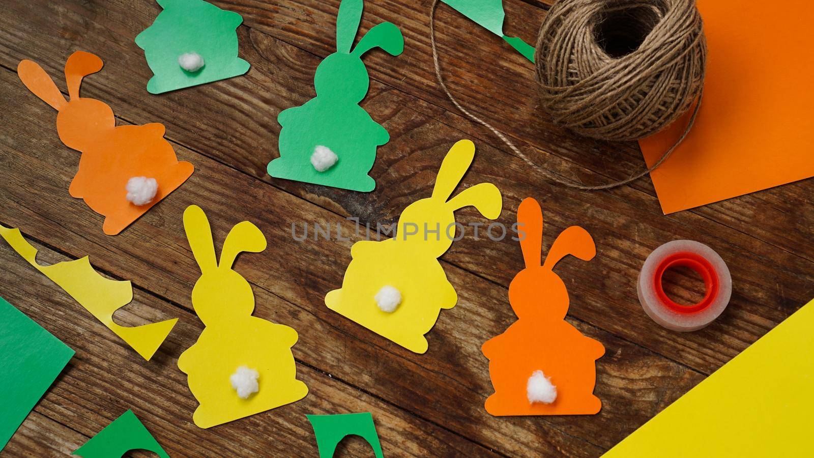 Easter bunnies made of paper on a wooden background. Create a decor for easter. DIY Easter garland making