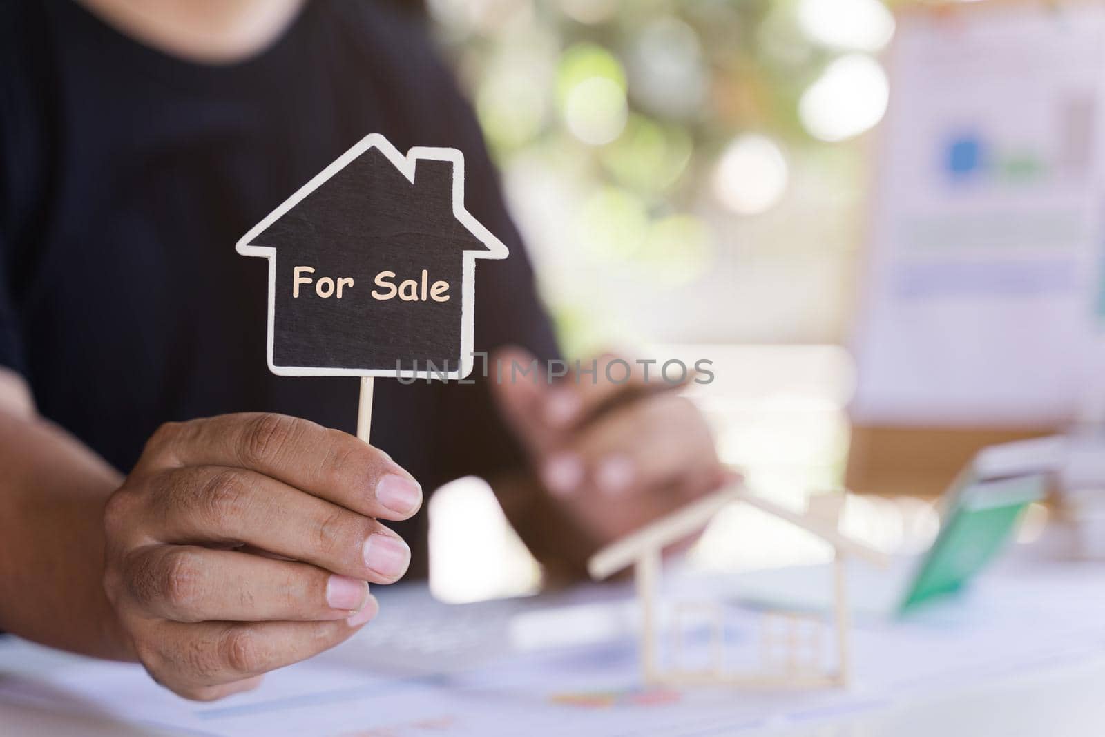 Home sale agent or house seller showing label house with text SALE. Mortgage concept. Real estate, moving home or renting property. by pravinrus