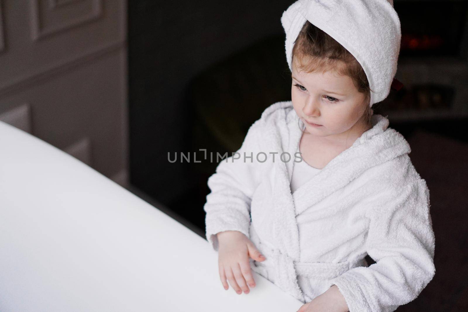 Little girl in a white robe after taking a bath. Hygiene and baby fashion concept