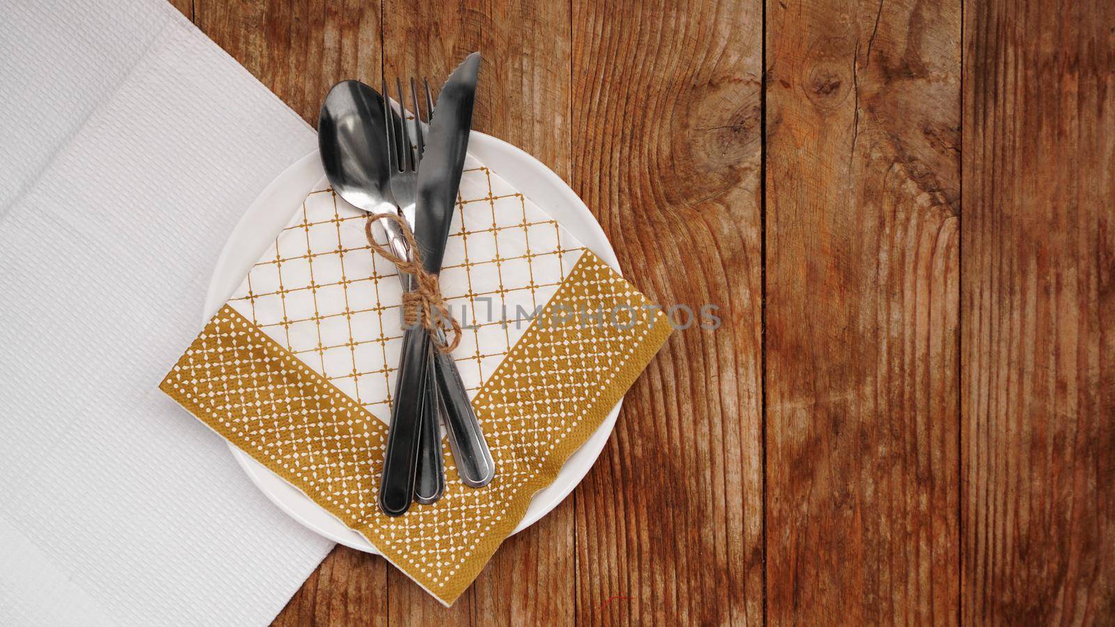 Place setting for dinner on rustic background. Christmas table setting with gold decorations on wooden table. Top view. Copy space.