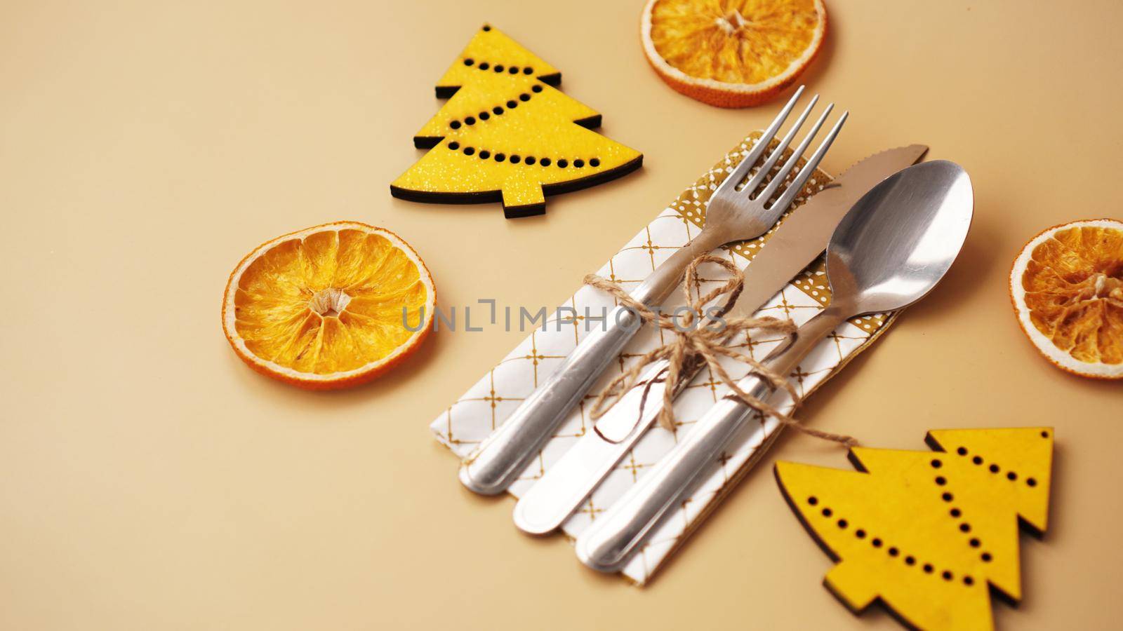 Setting of table with dry orange and wooden christmas figurines on gold background