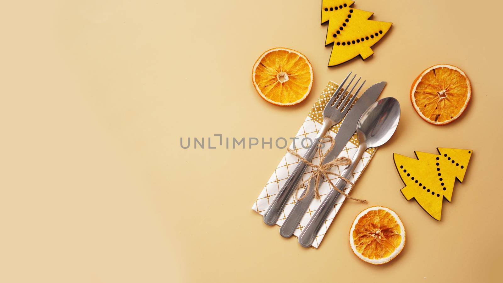 Setting of table with dry orange and wooden christmas figurines on gold background