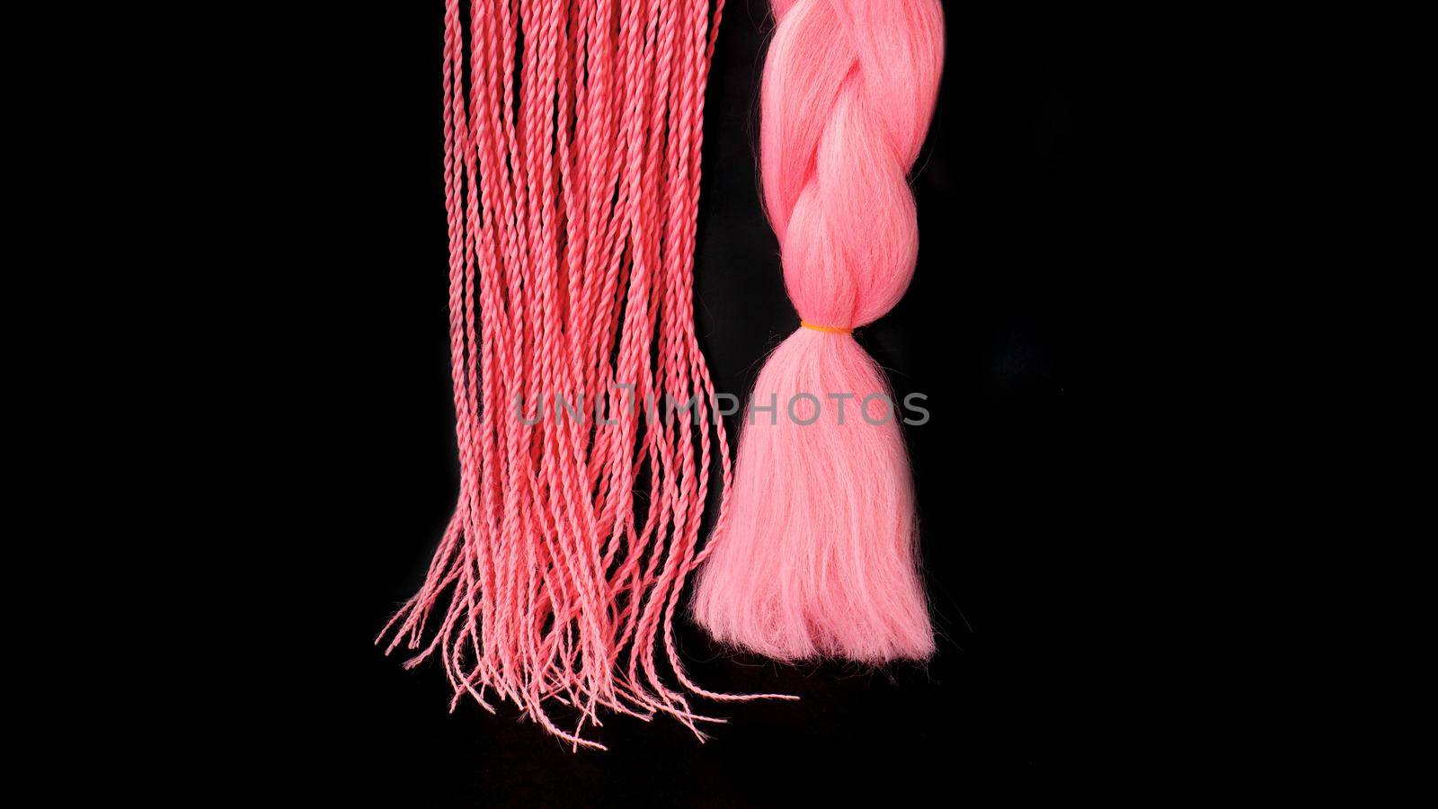 Pink kanekalon hangs and braids on a black background