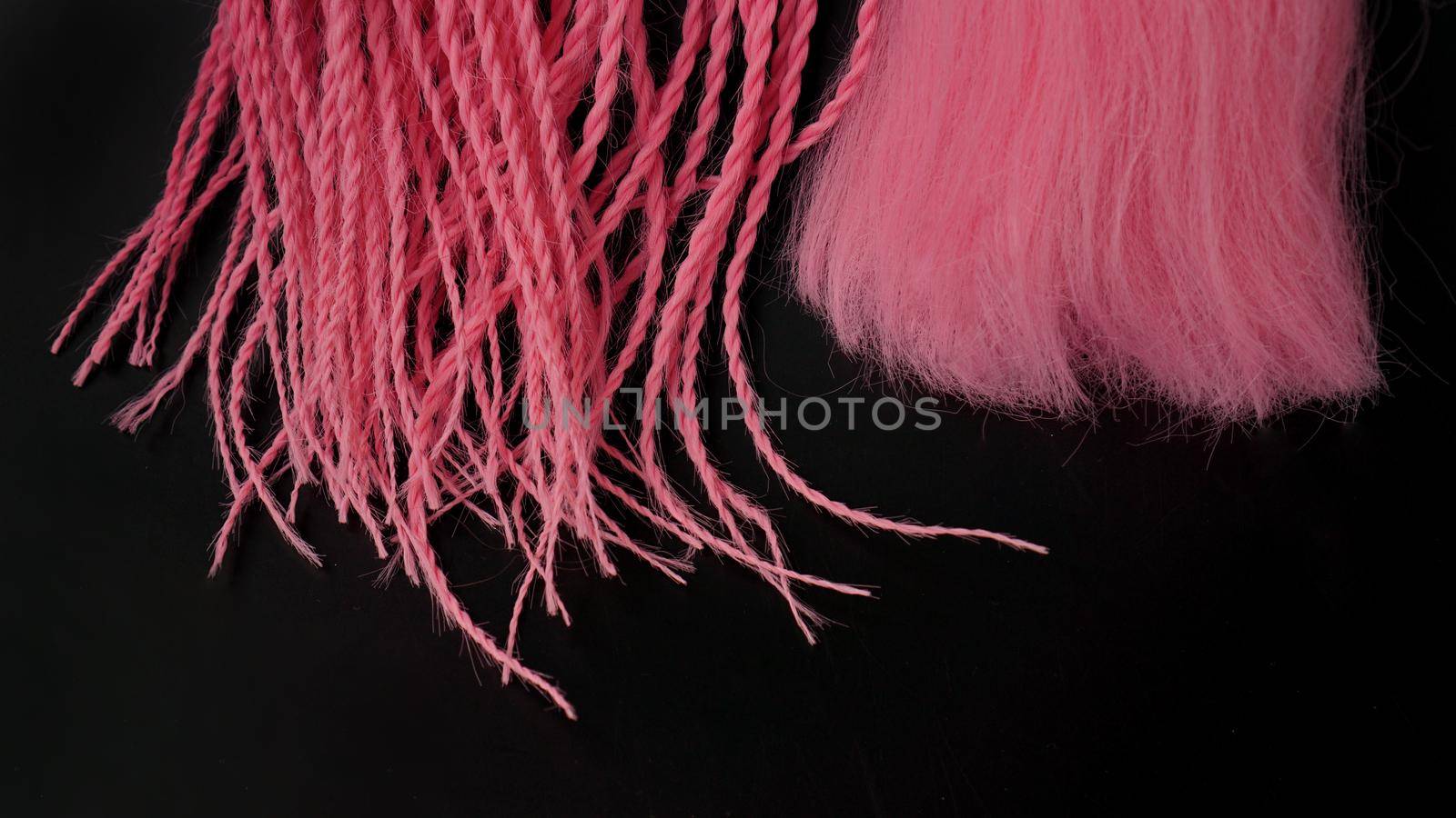 Pink kanekalon hangs and braids on a black background - tips close up