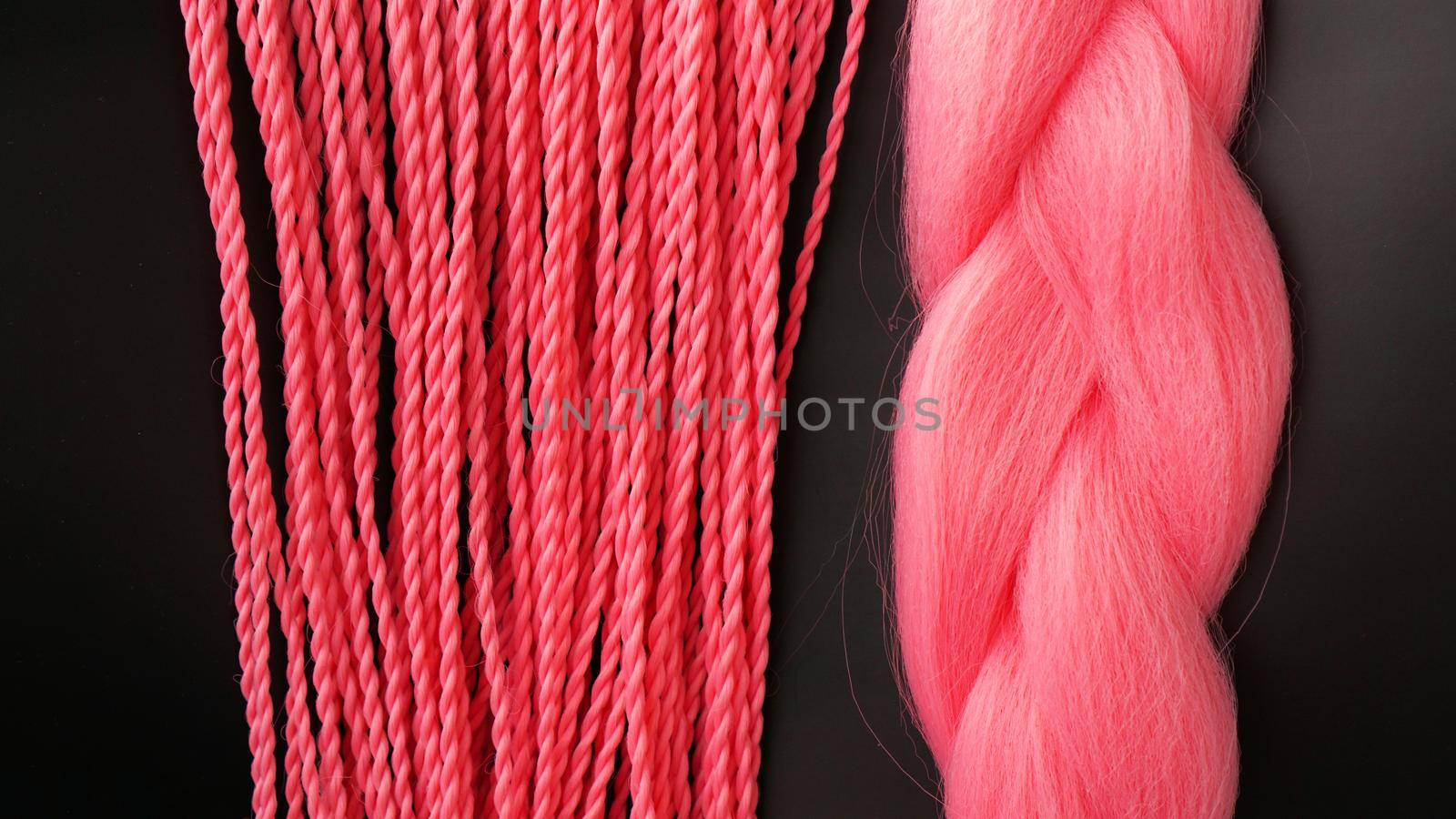 Pink kanekalon hangs and braids on a black background