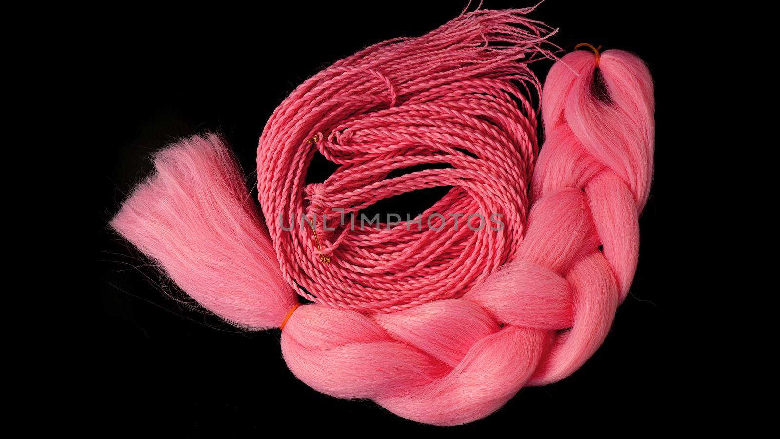 Pink kanekalon hangs and braids on a black background