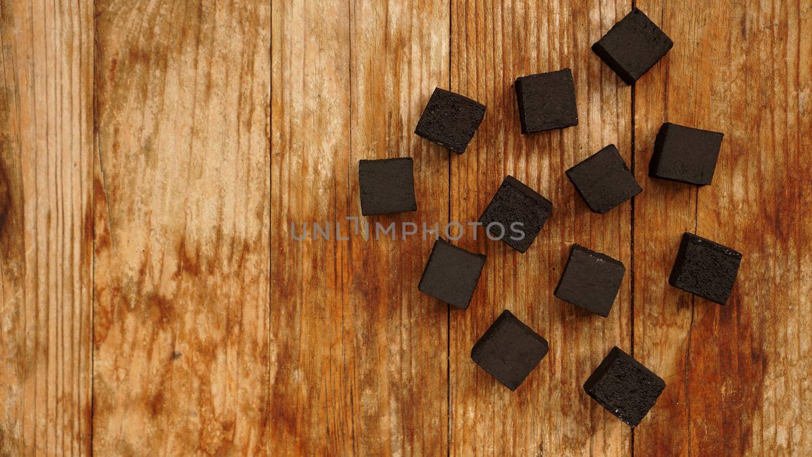 Cubes of coconut coal for hookah on wooden background. Top view, place for text