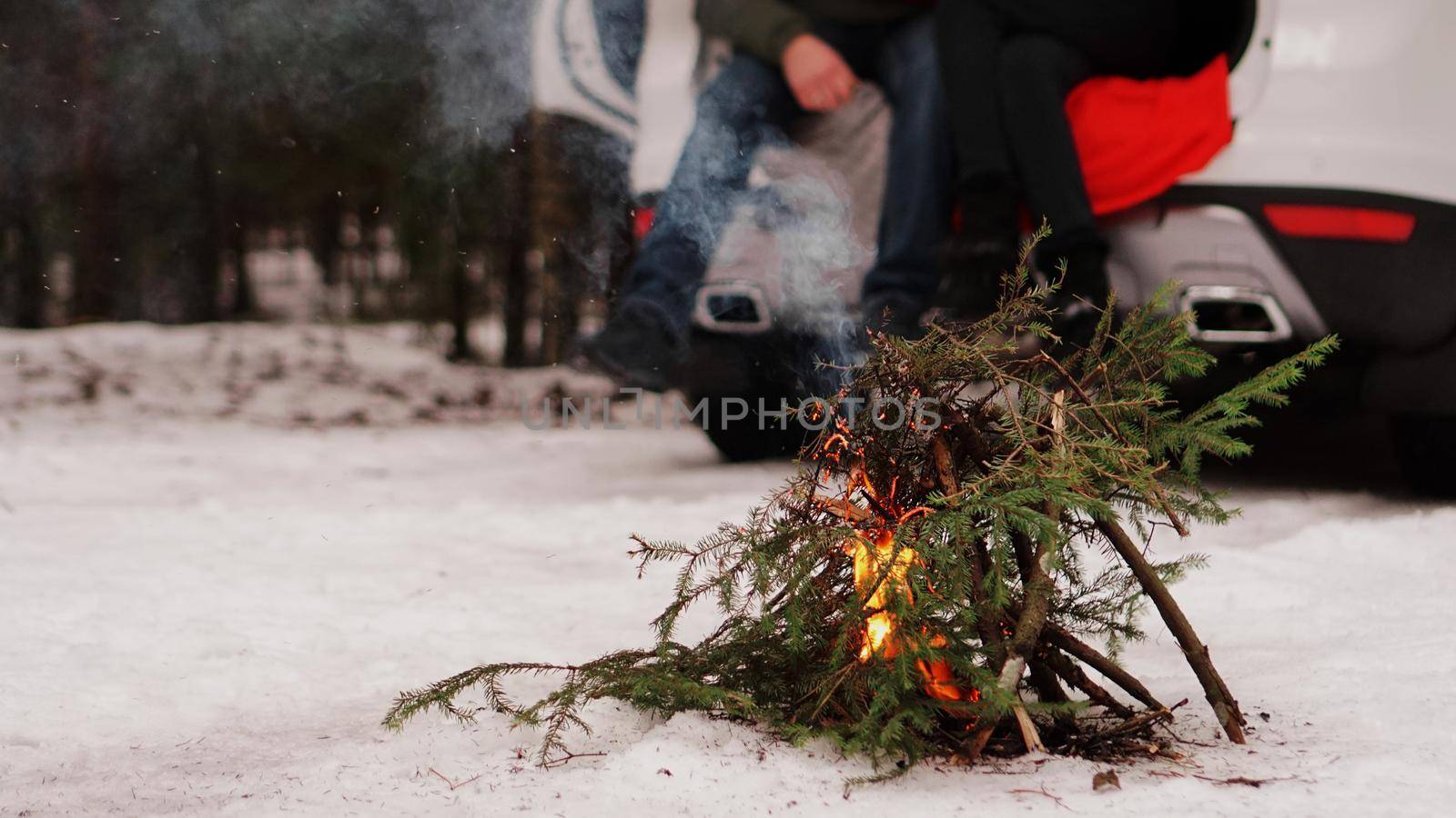 Bonfire of fir branches in the winter forest - Loving couple in truck at blurred background
