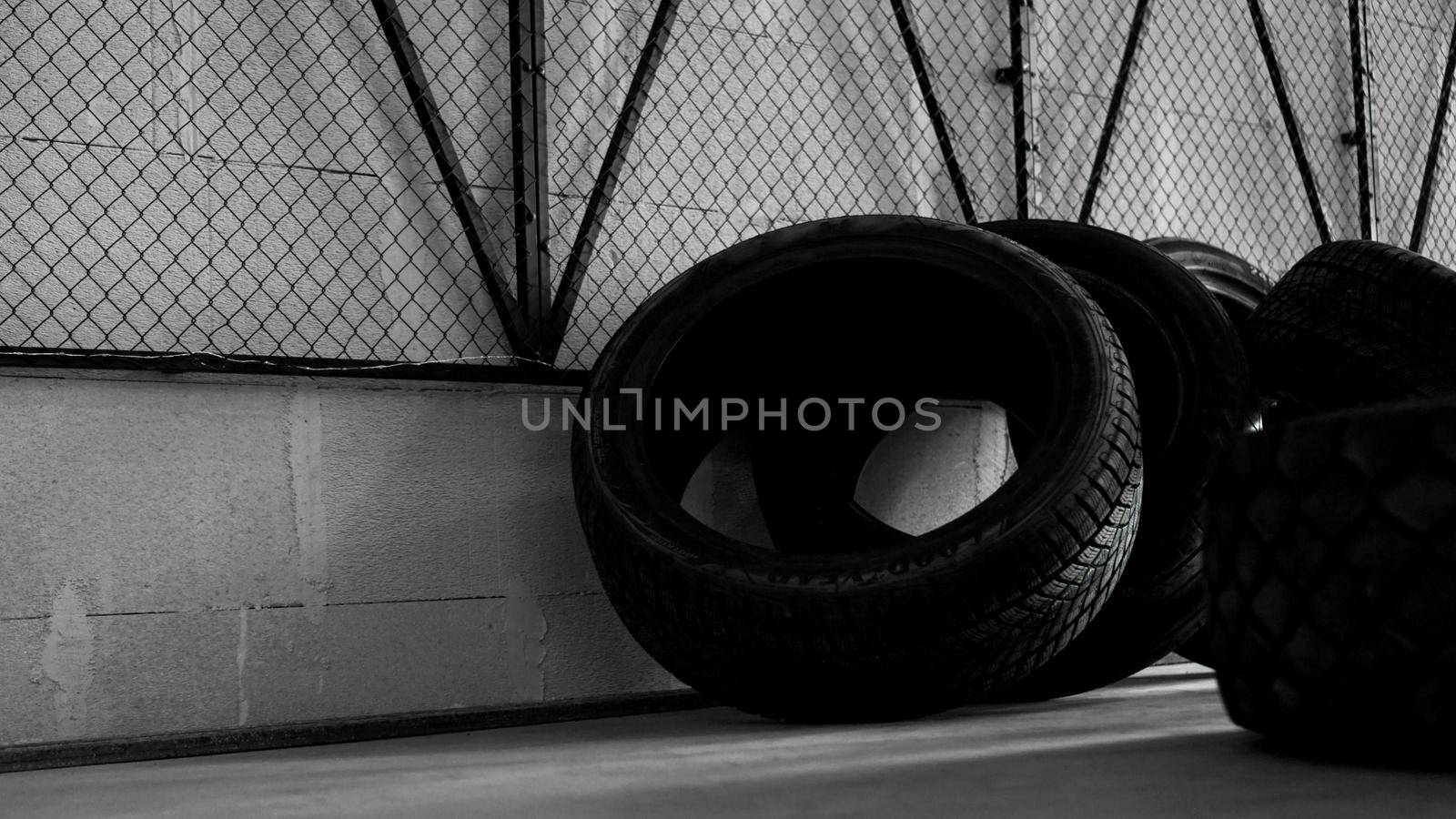 Tire warehouse. Four tires on the concrete floor. Black mesh on the wall. Brutal photo
