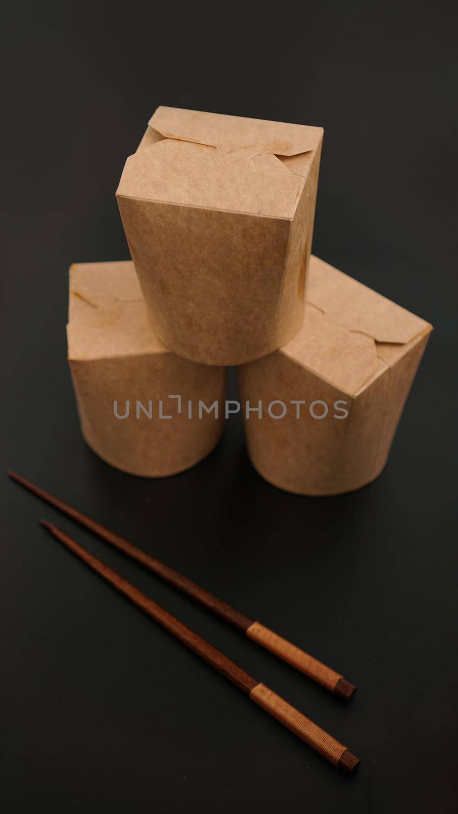 Brown paper cardboard food container on black background. Asian food delivery. Wok packaging