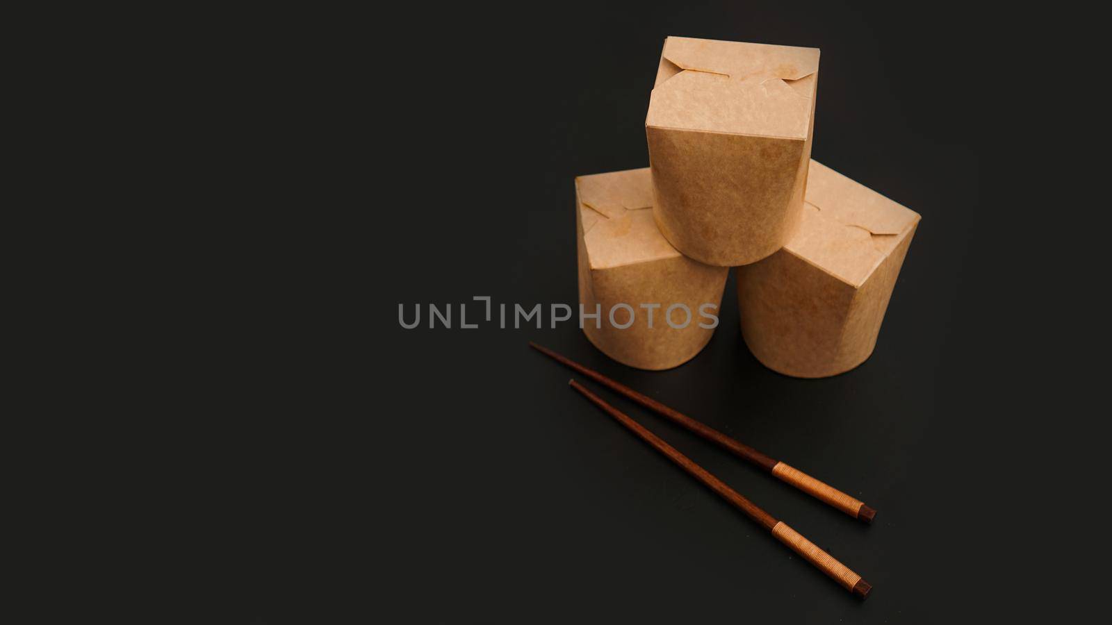 Brown paper cardboard food container on black background. Asian food delivery by natali_brill