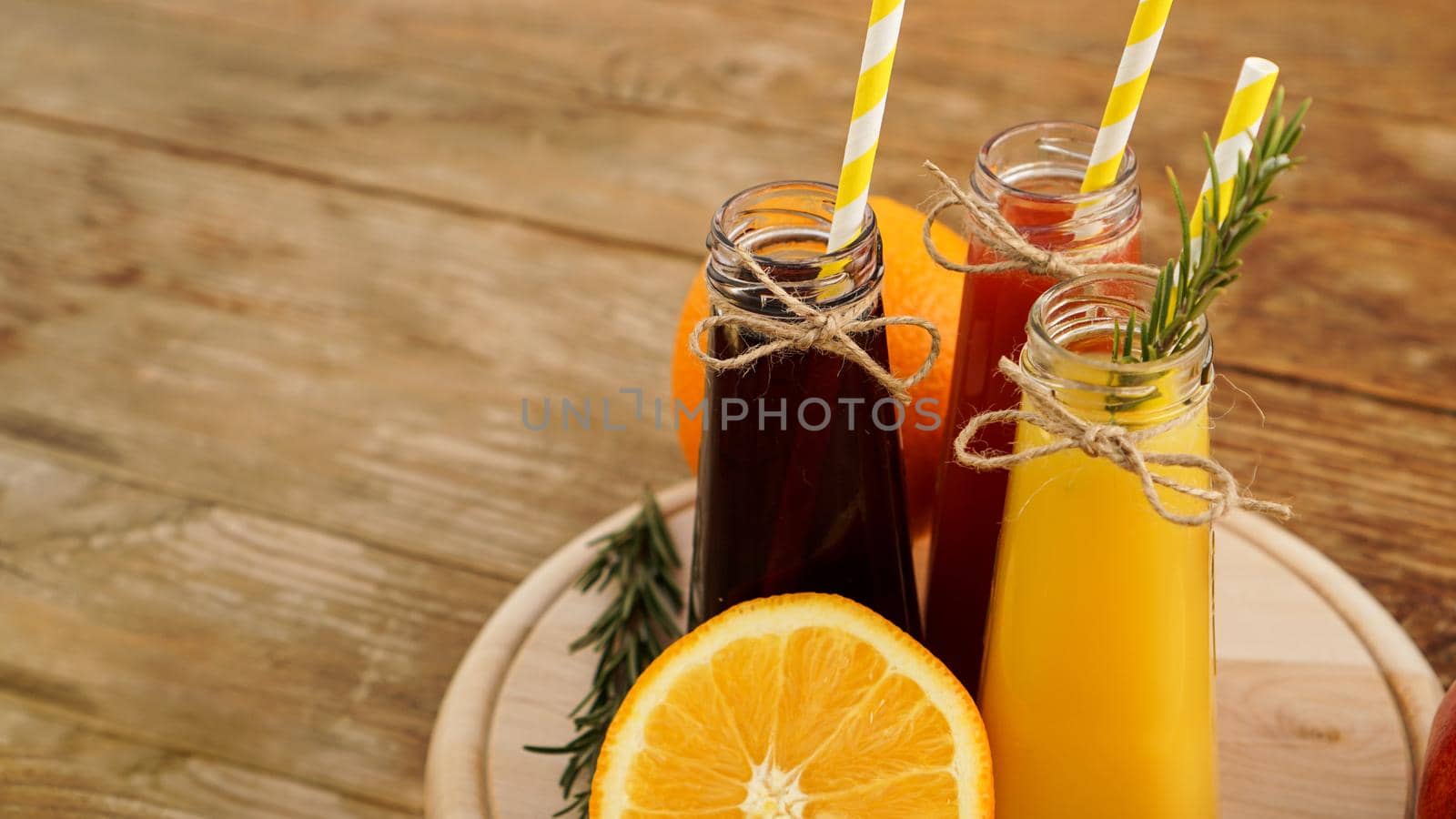 Home made lemonade in little bottles. Multicolored juices and fruits on wooden background