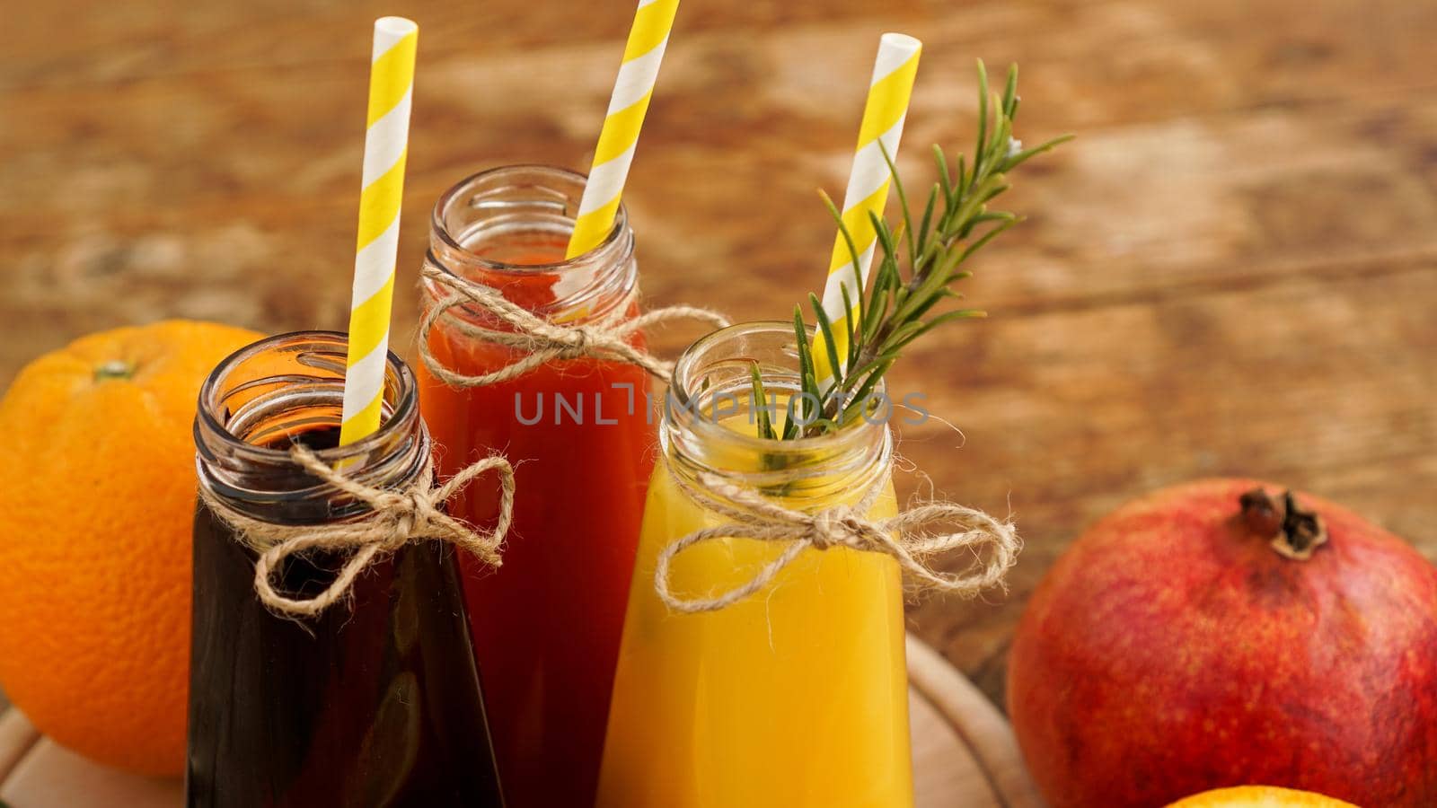 Home made lemonade in little bottles. Multicolored juices and fruits on wooden background