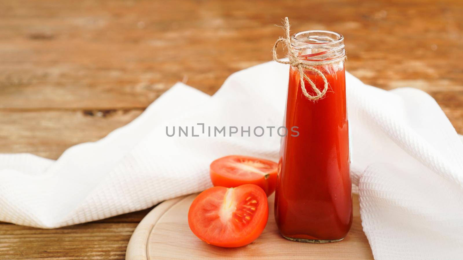 Tomato juice in glass bottle and fresh tomatoes on wooden background by natali_brill